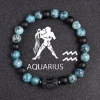 Zodiac bracelet, Aquarius option, with blue-green jasper, matte black onyx, hematite spacers, and a black Aquarius centerpiece, shown in a focused full product view on dark fabric.
