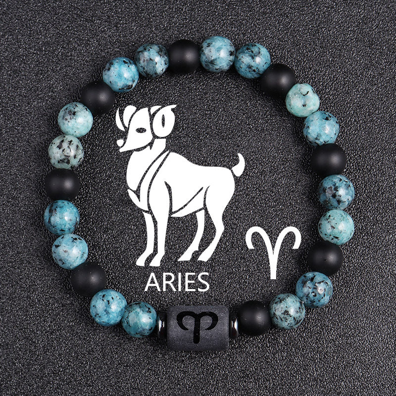 Zodiac bracelet, Aries option, with blue-green jasper, matte black onyx, hematite spacers, and a black Aries centerpiece, shown in a clear focused full product view on dark fabric.