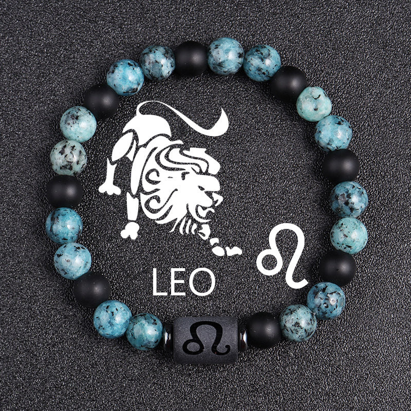 Zodiac bracelet, Leo option, with blue-green jasper, matte black onyx, hematite spacers, and a black Leo centerpiece, shown in a clear detailed focused product view on dark fabric.