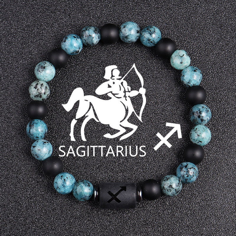 Zodiac bracelet, Sagittarius option, with blue-green jasper, matte black onyx, hematite spacers, and a black Sagittarius centerpiece, shown in a simple product view on dark fabric.