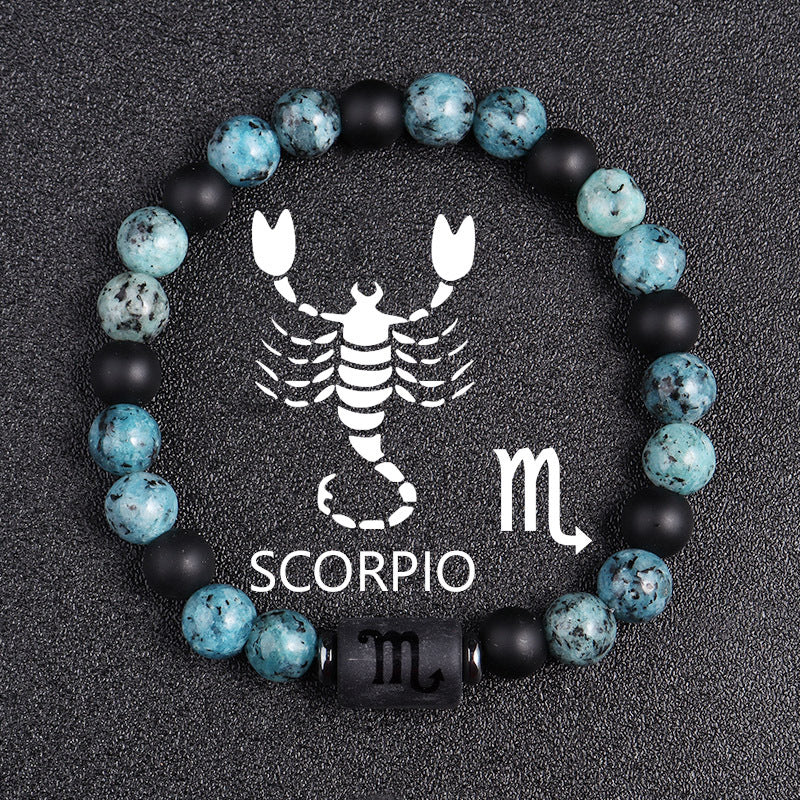 Zodiac bracelet, Scorpio option, with blue-green jasper, matte black onyx, hematite spacers, and a black Scorpio centerpiece, shown in a clear detailed product view on dark fabric.